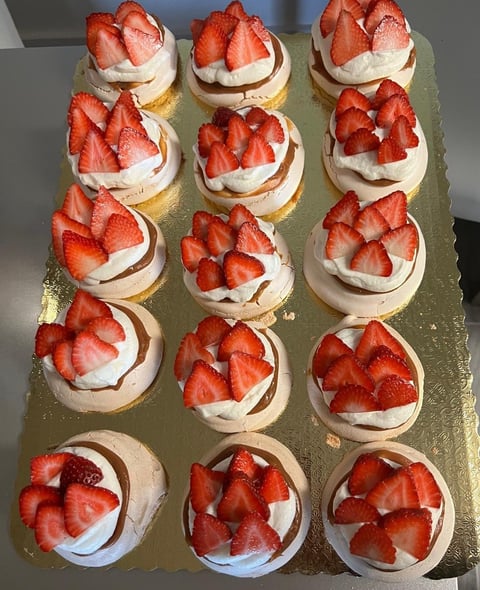 Grid of 15 mini desserts topped with fresh strawberries and cream on a gold cake board