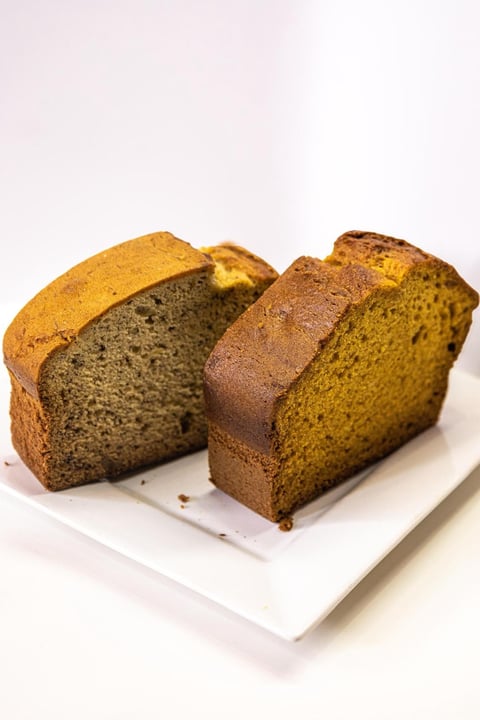 Two slices of spiced loaf cake with moist crumb texture on a white plate, showing poppy seed and chocolate varieties