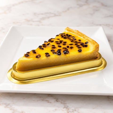 Slice of passion fruit tart with caramelized sugar dots on a gold base, served on a white plate