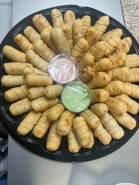 Black platter of croissants arranged in a circle with two small bowls of dipping sauces in the center
